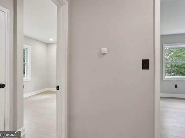 hallway featuring light wood finished floors and baseboards