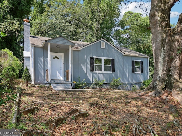 view of front of house featuring a chimney, board and batten siding, and roof with shingles
