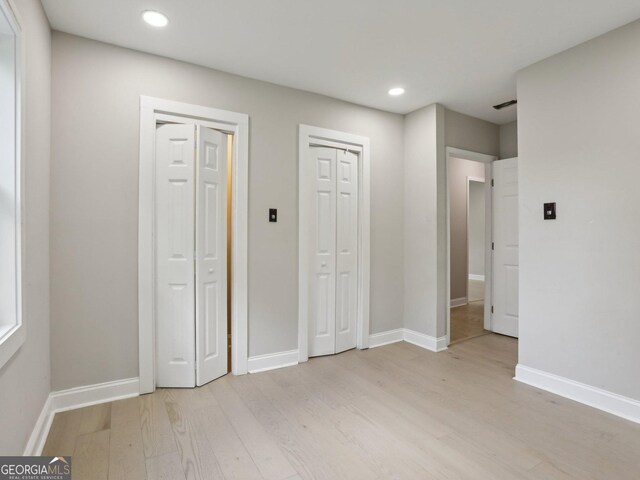 unfurnished bedroom featuring light wood-style floors, multiple closets, recessed lighting, and baseboards