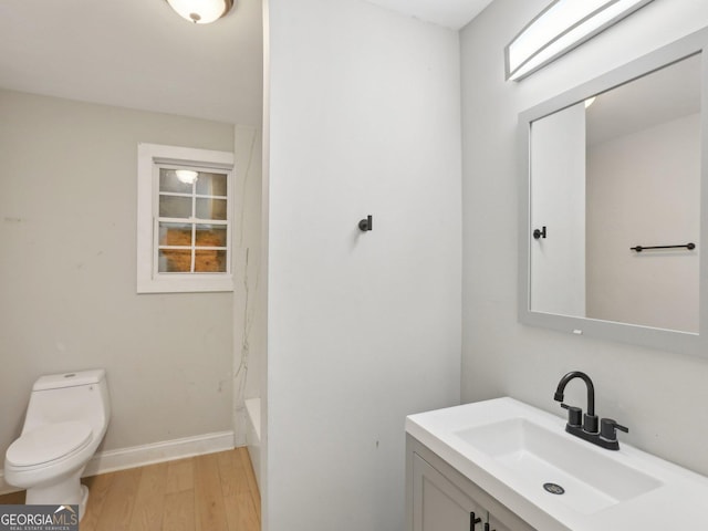 full bathroom featuring wood finished floors, toilet, vanity, and baseboards