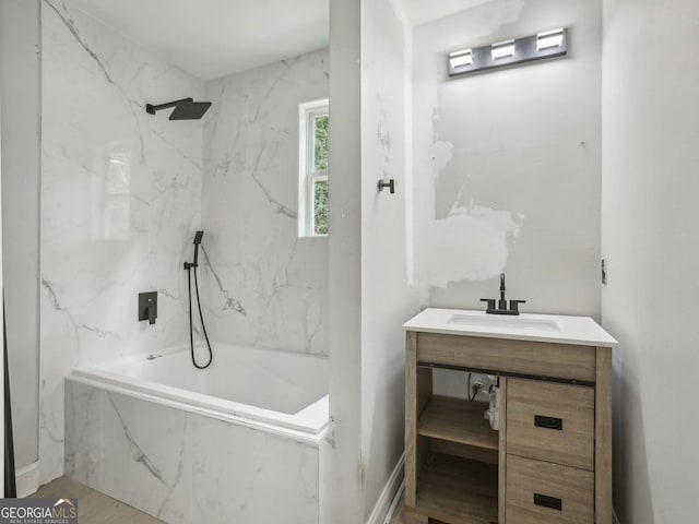 bathroom featuring a tub with marble appearance, a marble finish shower, and vanity