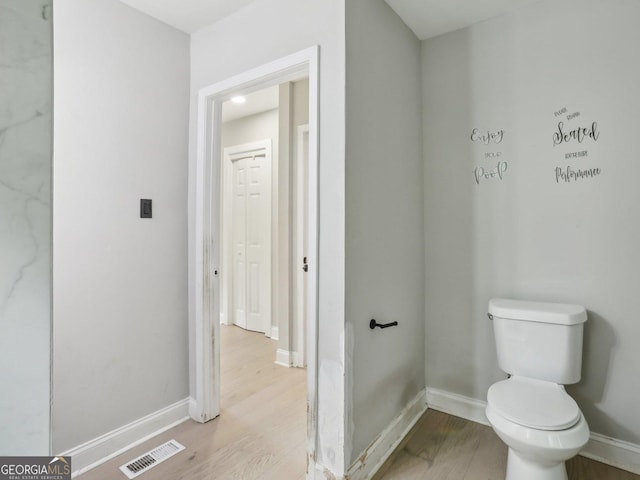 bathroom with baseboards, visible vents, wood finished floors, and toilet