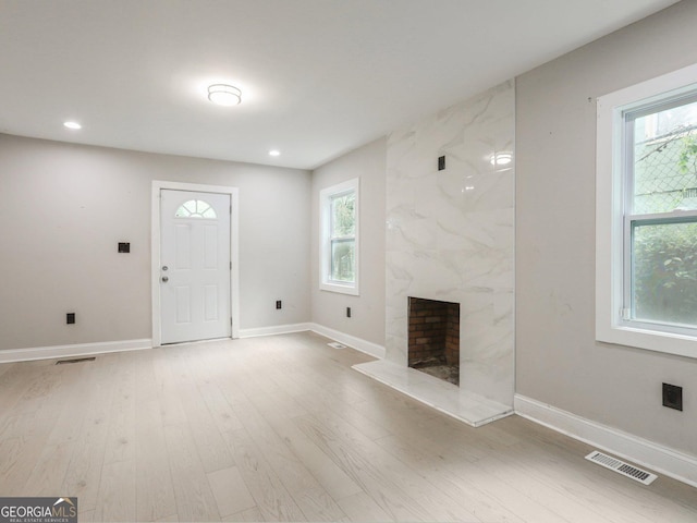 interior space with recessed lighting, light wood-style flooring, a premium fireplace, baseboards, and visible vents