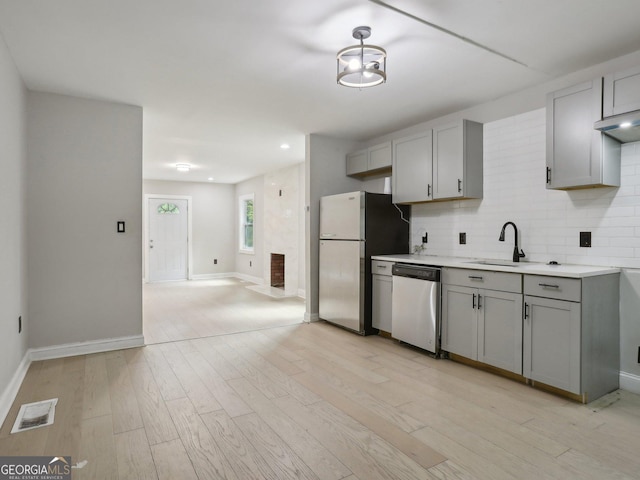 kitchen featuring light countertops, stainless steel dishwasher, freestanding refrigerator, and gray cabinets