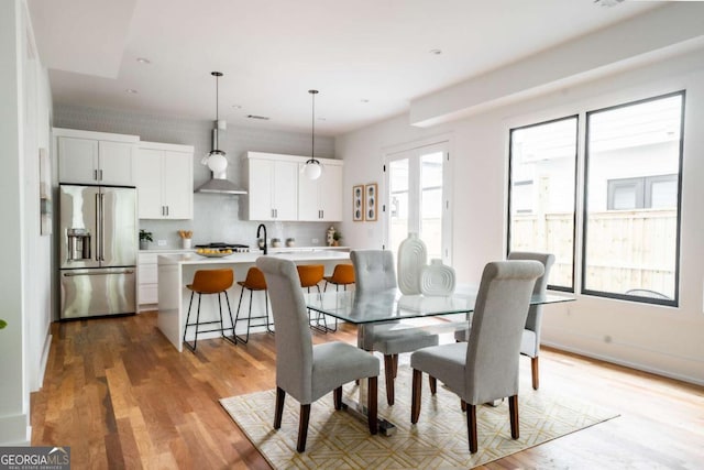 dining space with plenty of natural light, sink, and light wood-type flooring