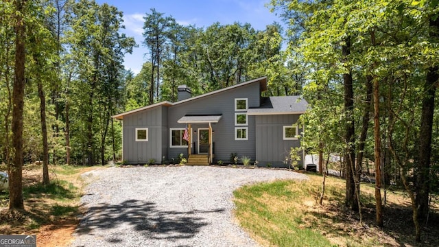 view of front facade featuring driveway, board and batten siding, and a chimney