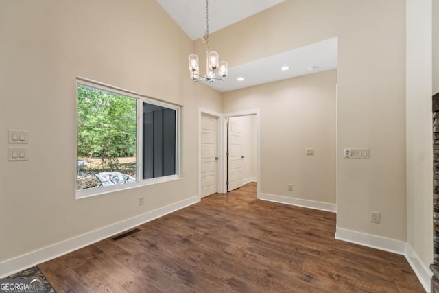 empty room featuring a chandelier, dark wood-type flooring, visible vents, and baseboards