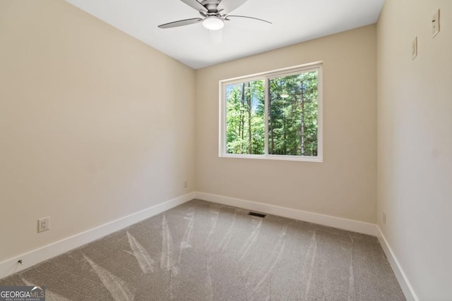 carpeted spare room featuring ceiling fan, visible vents, and baseboards