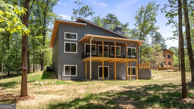 back of property featuring board and batten siding, a yard, and a chimney