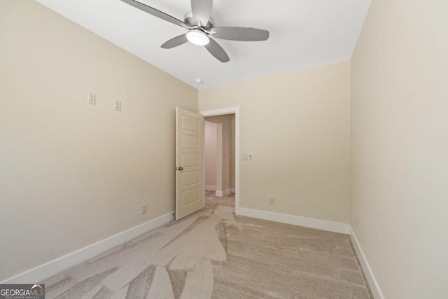 spare room with a ceiling fan, light carpet, and baseboards