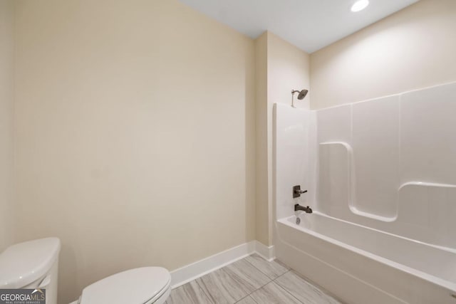 full bathroom featuring toilet, baseboards, and shower / washtub combination