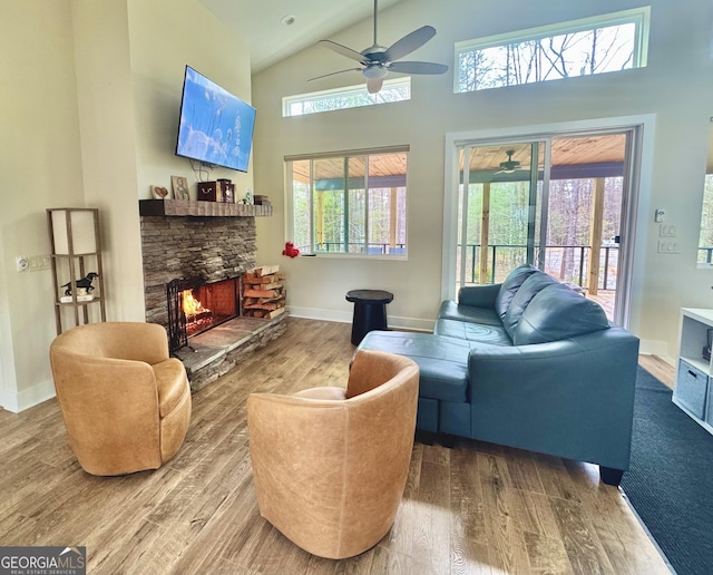 living room with a stone fireplace, wood finished floors, and a healthy amount of sunlight