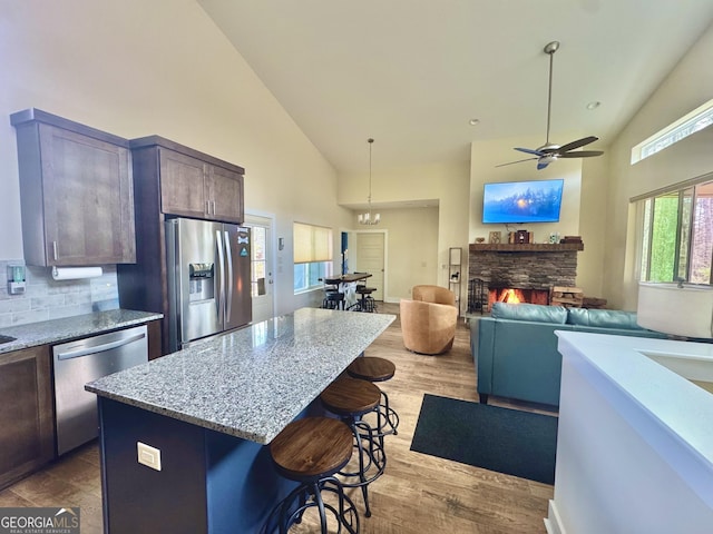 kitchen featuring light stone counters, stainless steel appliances, a breakfast bar, a fireplace, and a center island