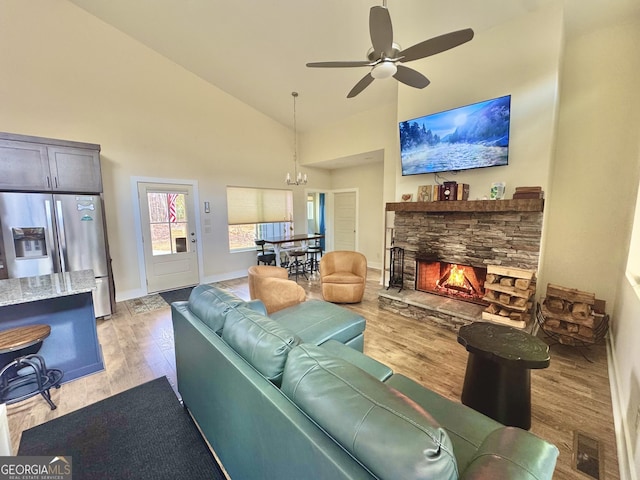 living area featuring visible vents, baseboards, light wood-type flooring, a fireplace, and high vaulted ceiling