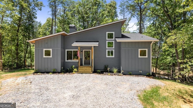 view of front of property featuring a shingled roof, a chimney, and board and batten siding