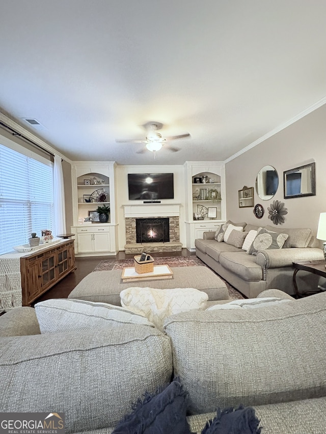 living room with crown molding, built in features, a fireplace, and ceiling fan