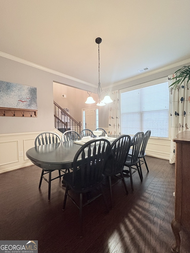 dining space featuring dark wood-type flooring, an inviting chandelier, and ornamental molding