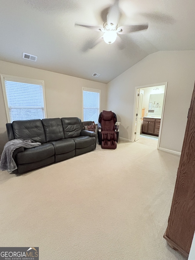 living room featuring ceiling fan, light colored carpet, a wealth of natural light, and lofted ceiling