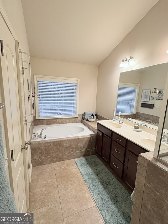 bathroom featuring vanity, a relaxing tiled tub, and tile patterned flooring