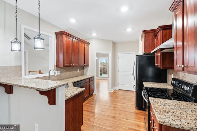 kitchen with electric range, a breakfast bar, a peninsula, light wood-style floors, and a sink