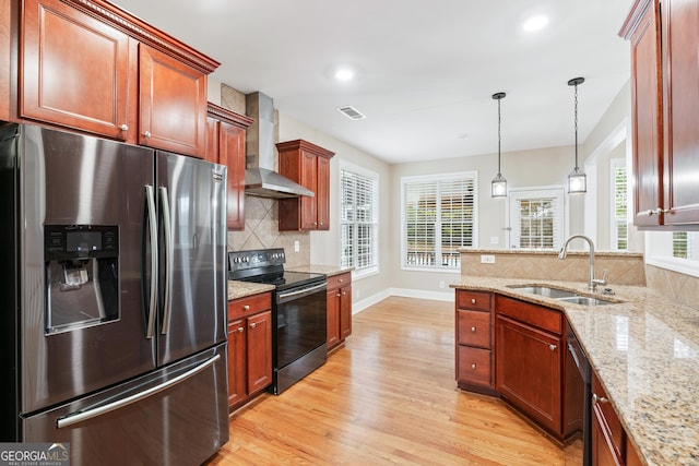 kitchen with black range with electric cooktop, a sink, light wood-style floors, wall chimney range hood, and stainless steel fridge