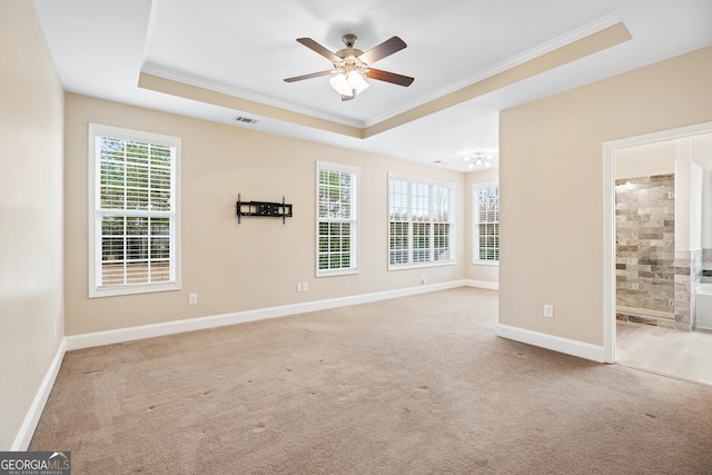 carpeted empty room featuring baseboards, a tray ceiling, plenty of natural light, and crown molding