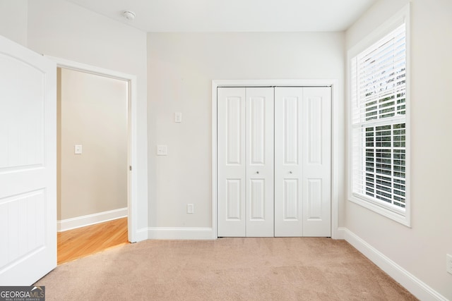 unfurnished bedroom with light carpet, baseboards, and a closet