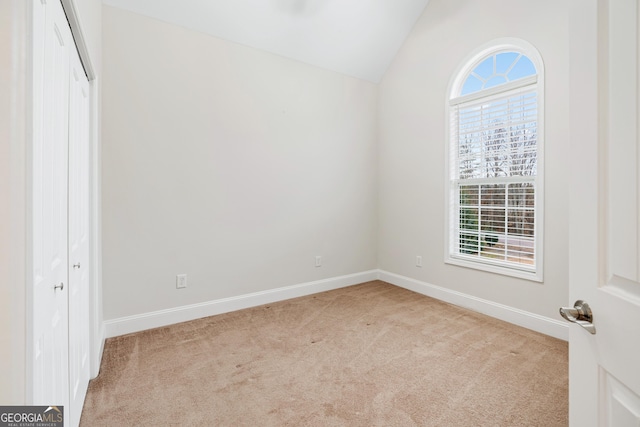 unfurnished bedroom with carpet floors, baseboards, a closet, and lofted ceiling