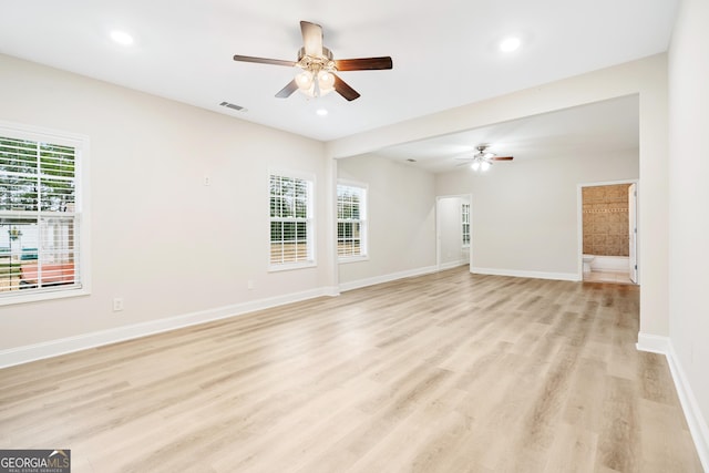 unfurnished living room with a wealth of natural light, light wood-style floors, visible vents, and baseboards