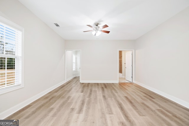 unfurnished room featuring light wood finished floors, a ceiling fan, visible vents, and baseboards