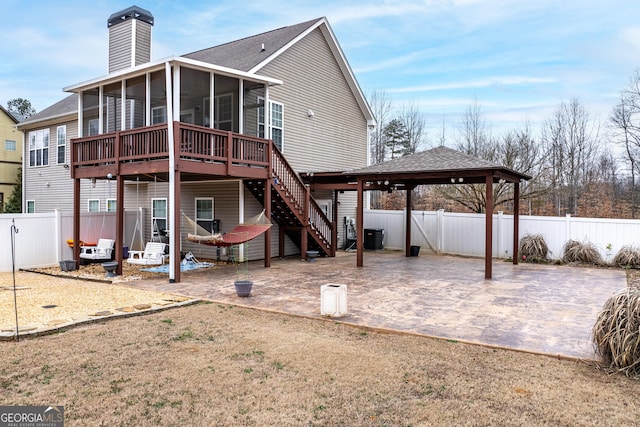 back of property featuring a chimney, stairway, a sunroom, a patio area, and a fenced backyard