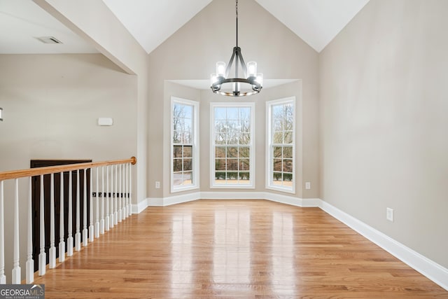 unfurnished dining area featuring light wood-style floors, vaulted ceiling, baseboards, and a chandelier