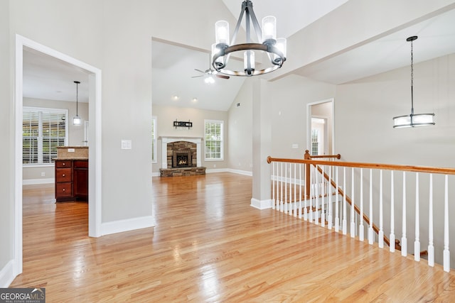 interior space featuring a chandelier, high vaulted ceiling, an upstairs landing, baseboards, and light wood-style floors