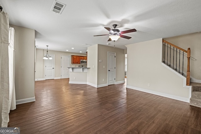 unfurnished living room featuring ceiling fan with notable chandelier and dark hardwood / wood-style floors