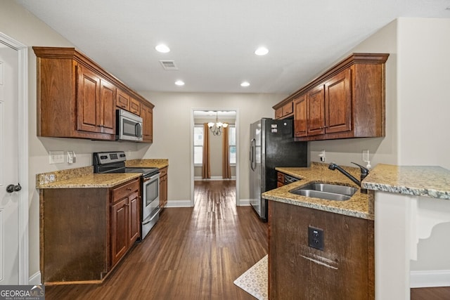 kitchen with sink, dark hardwood / wood-style floors, light stone countertops, and appliances with stainless steel finishes