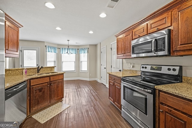 kitchen with sink, hanging light fixtures, light stone countertops, and appliances with stainless steel finishes