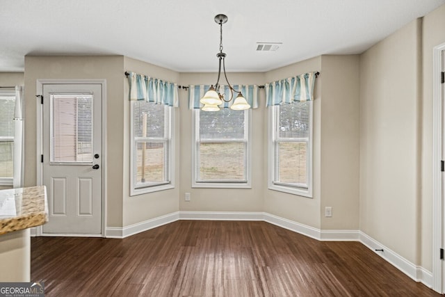 unfurnished dining area with dark hardwood / wood-style floors, an inviting chandelier, and a healthy amount of sunlight