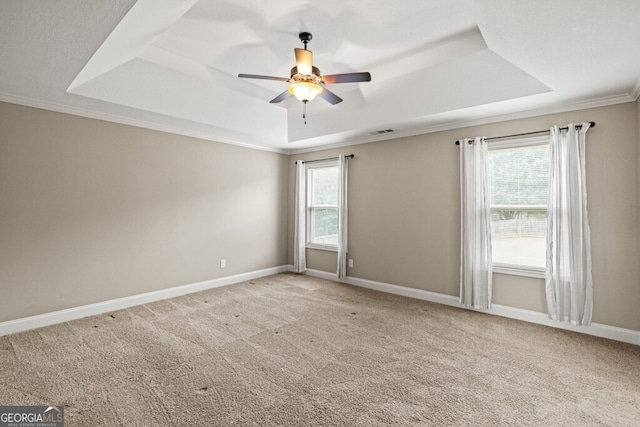 carpeted spare room with crown molding, ceiling fan, and a raised ceiling