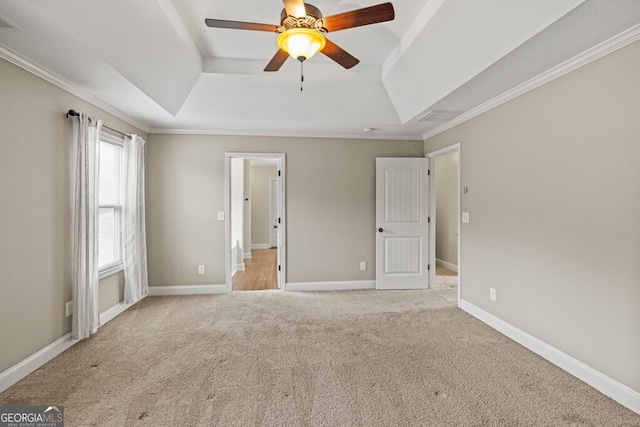 unfurnished bedroom featuring ceiling fan, light colored carpet, ornamental molding, and a raised ceiling