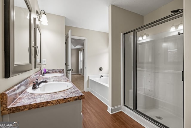 bathroom with wood-type flooring, vanity, and shower with separate bathtub