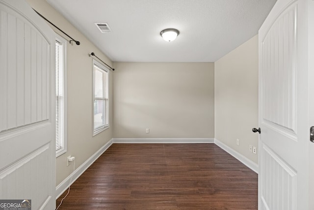 spare room featuring dark wood-type flooring and a textured ceiling