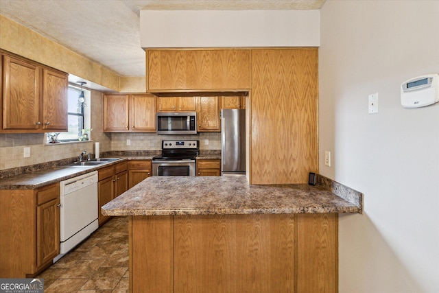 kitchen featuring kitchen peninsula, backsplash, sink, and stainless steel appliances