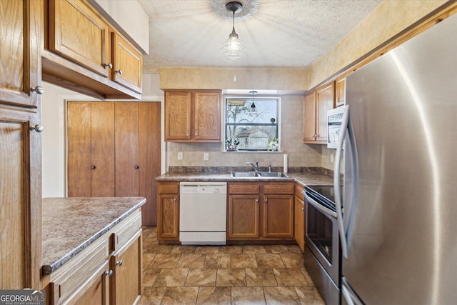 kitchen with appliances with stainless steel finishes, a textured ceiling, tasteful backsplash, hanging light fixtures, and sink