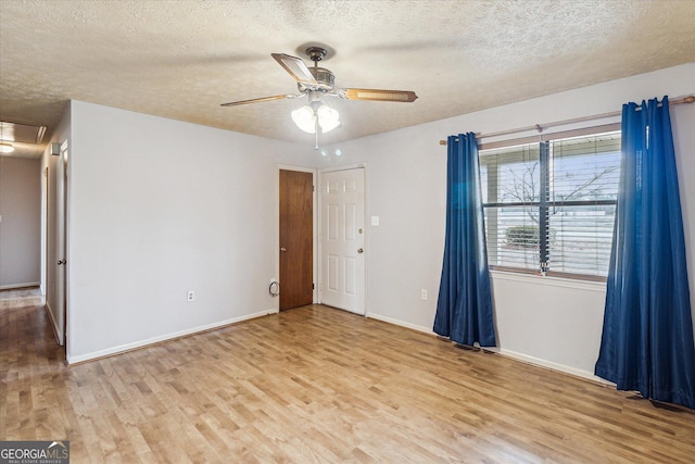 spare room with ceiling fan, a textured ceiling, and light wood-type flooring