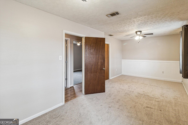 carpeted spare room with ceiling fan and a textured ceiling