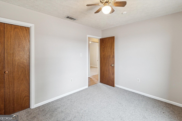 unfurnished bedroom with a closet, ceiling fan, a textured ceiling, and carpet floors