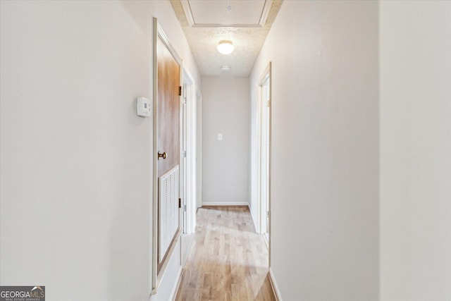 hallway featuring a textured ceiling and light hardwood / wood-style flooring