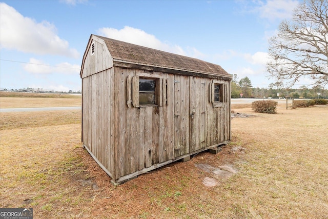 view of outbuilding with a lawn and a rural view