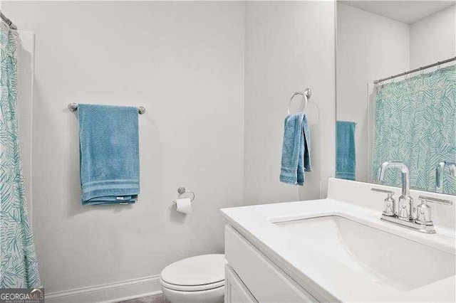 full bathroom with toilet, vanity, and baseboards