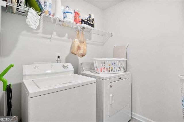 clothes washing area featuring washing machine and dryer, laundry area, and baseboards